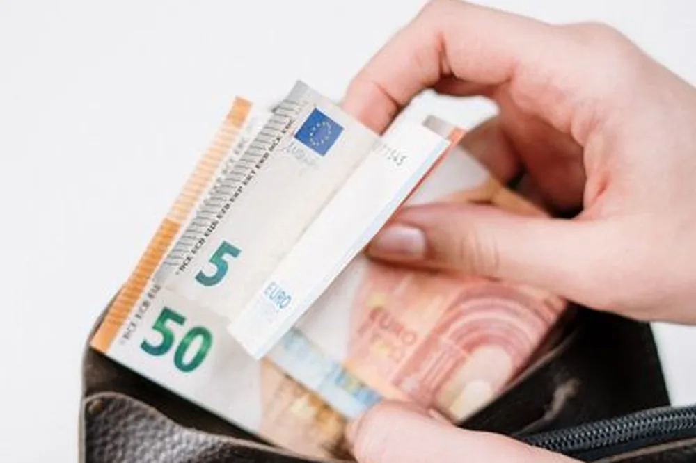 Gros plan sur des mains plaçant des billets en euros dans un portefeuille. Idéal pour un contenu lié à la finance.