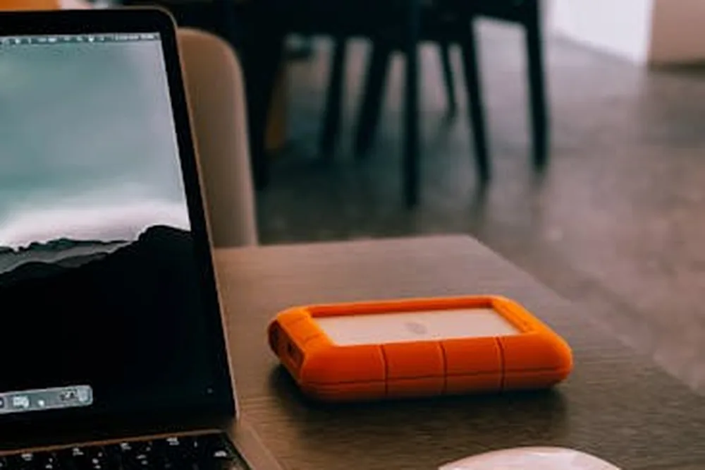 Un espace de travail intérieur confortable comprenant un ordinateur portable, un disque dur, une souris et des écouteurs.