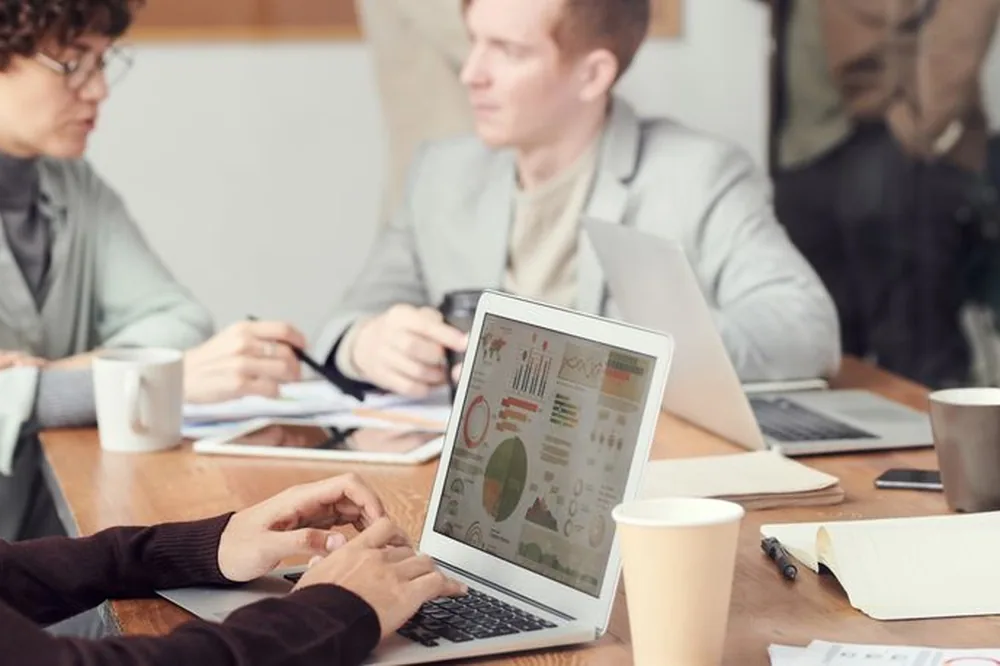 Des professionnels collaborant dans un cadre de bureau, concentrés sur l'analyse des données numériques lors d'une réunion.